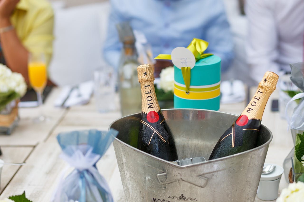 Elegant setup featuring champagne bottles in ice bucket and wrapped gift, perfect for celebrations.