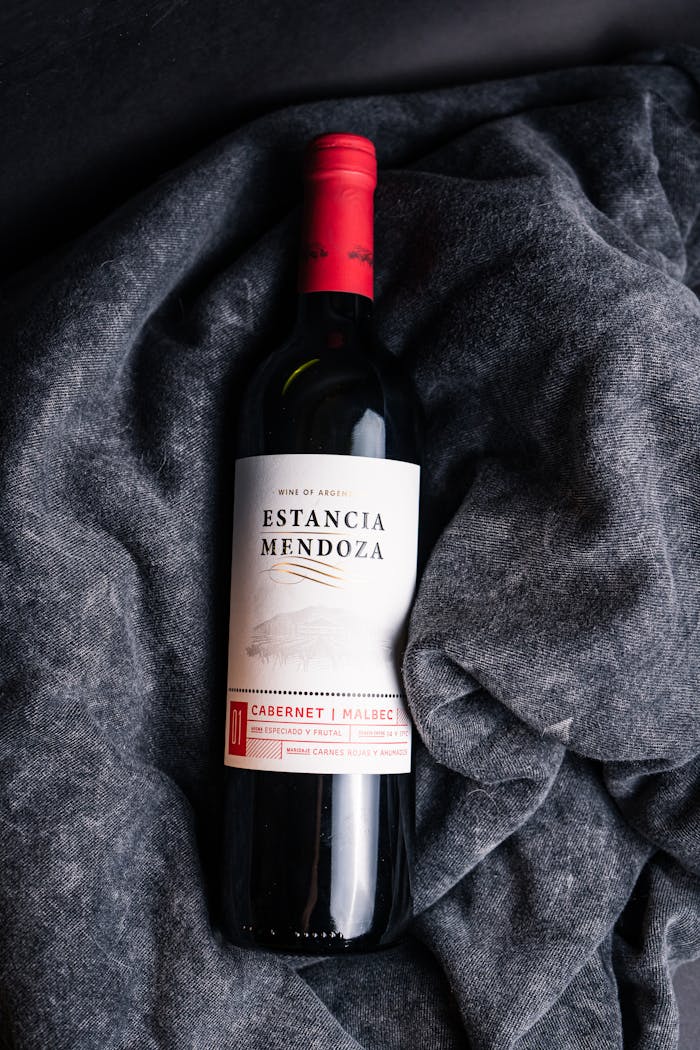 Elegant Estancia Mendoza Cabernet Malbec bottle on gray fabric, exuding luxury and indulgence.